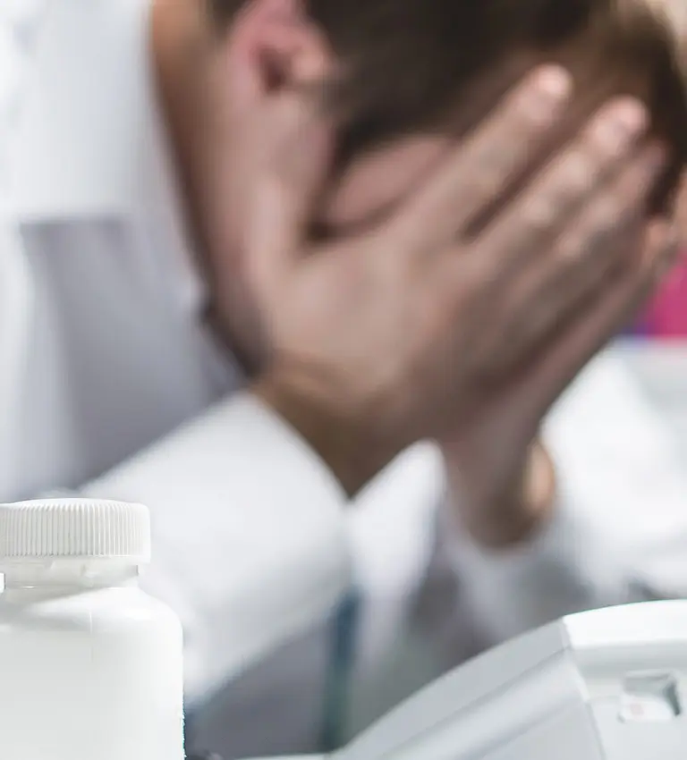 a man with a bottle of medicine in front of a computer