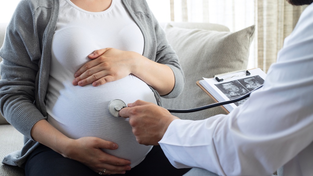 doctor with a stethoscope examines a pregnant woman