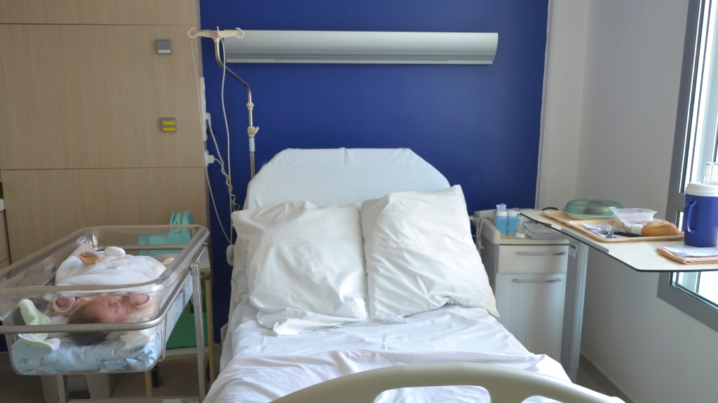 Empty hospital bed for patient and newborn baby near the bed