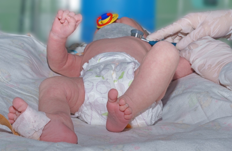 Doctor holding phonendoscope and doing auscultation newborn baby