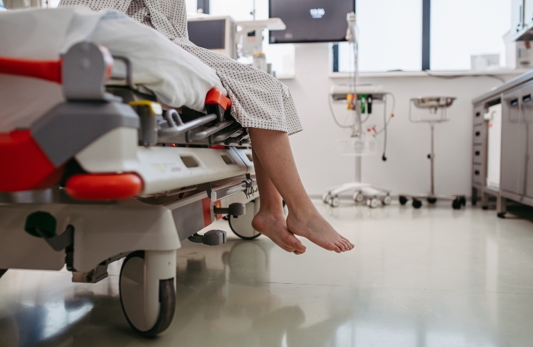 barefoot legs of patient, sitting on hospital bed in emergency room