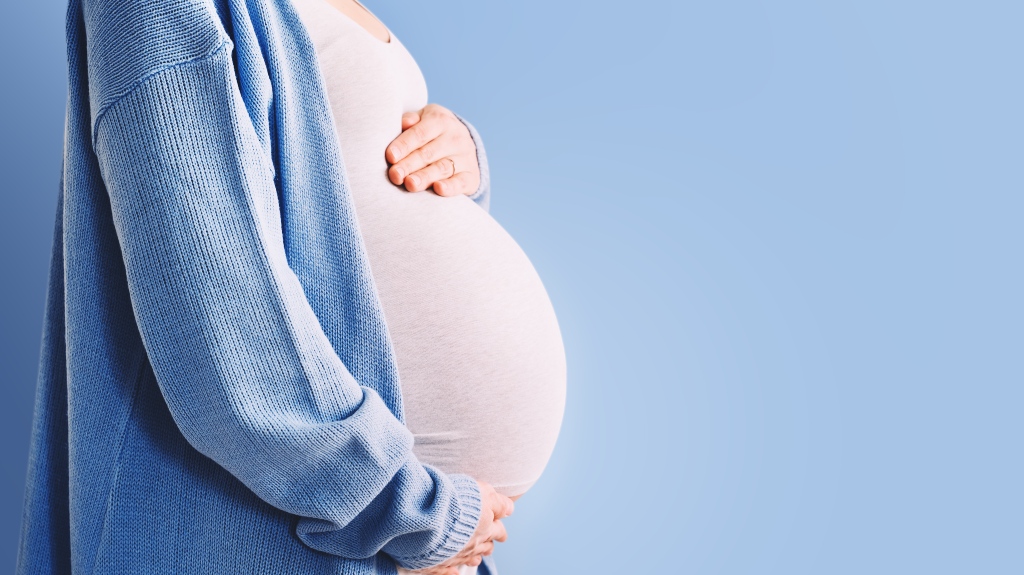 pregnant woman hugging her belly in blue background