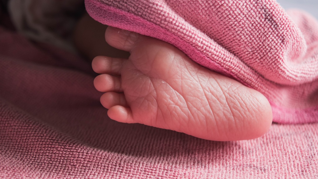 right foot of newborn baby under pink blanket