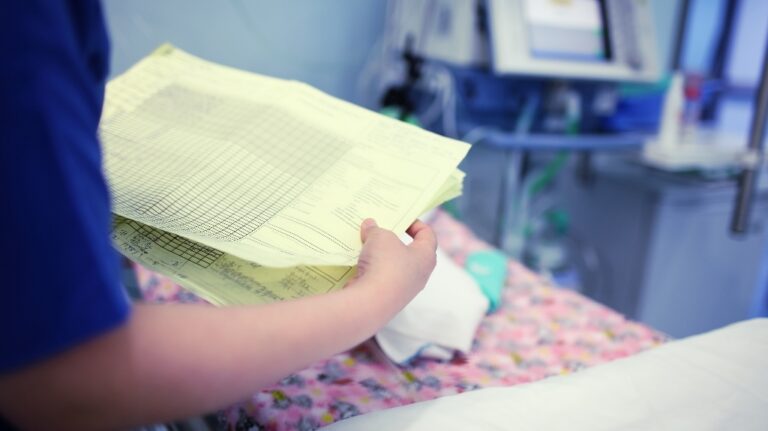 Female doctor looking to the baby patient medical card