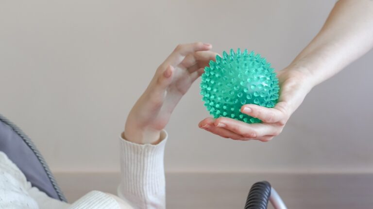 hands of a child with cerebral palsy exercises with a ball