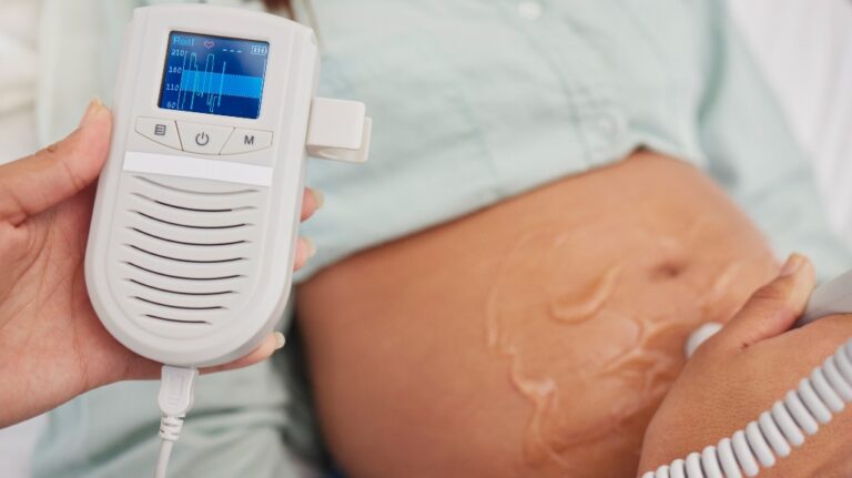 Pregnant woman, doctor hands and heart rate monitor